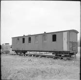 Skrotfärdig Nättraby - Alnaryd - Älmeboda Järnväg, NAEJ personvagn uppställd på provisorisk järnväg. Framför vagnen ses ett industrilok.