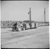 Gods transporteras av traktor på kaj.