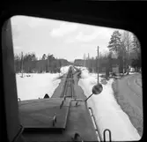 Vy över järnvägsspår med växel och hållplats.