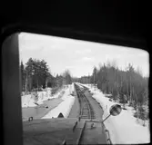 Vy över järnvägsspår med växel och hållplats.