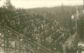 Vykort med motiv över publiken på läktarplats under Sundsvalls spelen 1918.