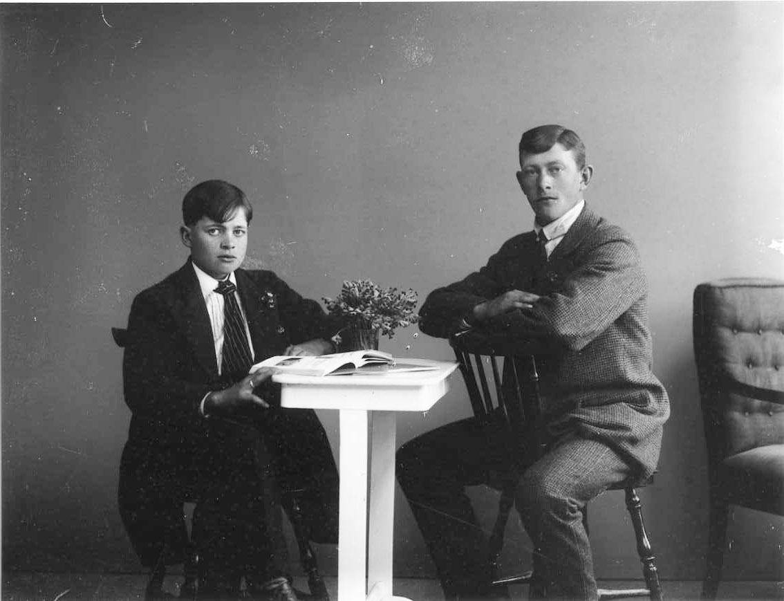Calla Helena Sundbeck, A group picture with two young men sitting at a table, with a busy book. Sven Blomkvist on the left with striped tie. Algot Lightweight to the right sits back on a chair and rests her arms on its backrest.