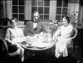 Josef Edhlund sitter vid kaffebordet tillsammans med två kvinnor klädda i sjukvårdsuniform, Östhammar, Uppland