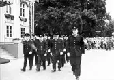 Brandkårens 50-årsjubileum. En grupp män i uniform går förbi Rådhuset medan en folksamling tittar på uppvisningen.