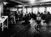 Bild tagen inifrån Alingsås Bil- och maskinverkstads maskinverkstad i kvarteret Månen 3-4. I lokalen ses 5 män som arbetar framför varsin maskin. 
Från vänster: Ragnar Karlsson, Bertil Wolin, Folke Johanssson, Sandstedt, Sven 