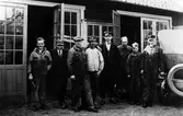 8 män utanför verkstaden i kv Månen 3-4, Alingsås Bil- och Motorverkstad. Längst till höger syns baksidan av en bil.
Från vänster: Charlie Hellberg, Katz, Gustav Andersson, Mattson, Eric Johansson, Harald Karlborg, Tore Adestål, Johan Dahlén.