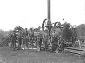 Arbetslag framför lokomobil som drev uppfodringsverk för torv på mossarna omkring Fåglaviks glasbruk.
Torven användes som bränsle på bruket.