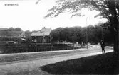 Södra Hamnvägen med järnvägsövergången vid ingången till Societetsparken i Varberg. Vid parken svänger Strandgatan söderut. I bakgrunden syns fästningen.