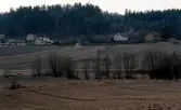 Vy över odlingsmark och Heljereds gårdar år 1978. Sandsjöbacka naturreservat ses i bakgrunden.
