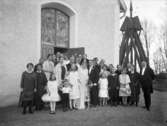 Almby kyrka i bakgrunden.
Bröllop. Brudpar och bröllopsgäster.
Handlare Harald Ström, Skänninge.