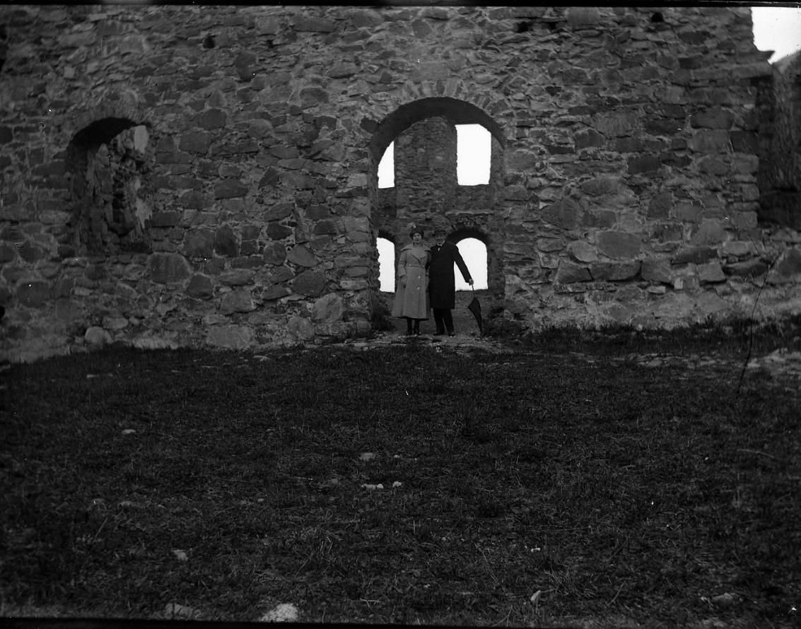 Anna Elisabet Karolina Rythén, A young woman and man stand in an electoral law opening to Brahehus castle ruin. They wear coat/rock and hat. It is possibly the siblings Anna-Lisa and Karl-Axel Rythén.