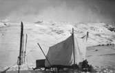 Uppspänt tält på kälke s.k. tältkälke  i snöigt fjällandskap. Forskningsresan som leddes av meteorogen Johan Wilhem Sandström i beskrivs av den då 19-åriga systerdottern och medhjälparen Thea Ahlberg i STF.S Årsbok 1928:

