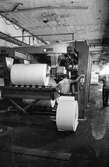 Män i arbete vid maskin på pappersbruket Papyrus i Mölndal, hösten 1970. Klipp 5 (arkmaskin), från baksidan, där man lade rullarna. byggnad 10.