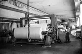 Man i arbete vid rullmaskin 5, byggnad 10 på pappersbruket Papyrus i Mölndal, hösten 1970. Mannen på bilden arbetar som rullare och sköter maskinen med hjälp av manöverbord.