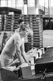 Män i arbete vid klipp på pappersbruket Papyrus i Mölndal, hösten 1970. KM 2, byggnad 6. Mannen i förgrunden väntar på arken som skall lyftas ur maskinen och läggas på pallen.