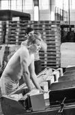Män i arbete vid klipp på pappersbruket Papyrus i Mölndal, hösten 1970. KM 2, byggnad 6. Mannen i förgrunden väntar på arken som skall lyftas ur maskinen och läggas på pallen.