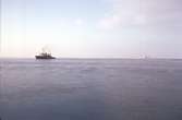 Ymer passerar isbrytaren Oden (troligen). I bakgrunden syns sju stycken olika fartyg.