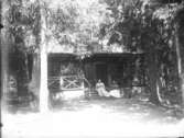 Hus med lång terrass samt två kvinnor, ca 1910.