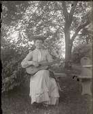 En dam som spelar gitarr, ca 1910.
