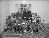 Man och kvinna sitter i en soffa omgivna av blommor, Östhammar, Uppland