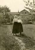 Hilma Eriksson (1878 - 1946) samt en okänd kvinna till höger, står i trädgården utanför 