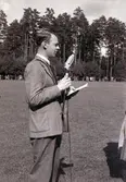 SM i gång på Värendsvallen, 1943.
En man i kostym, talar i mikrofon på planen.