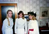 Luciatåg i Brattåshemmets matsal, december 1978. Linda Dahlgren är Lucia, övriga namnuppgifter saknas. Troligtvis har kvinnorna fått var sitt halssmycke som gåva, vilket de bär runt halsen. I bakgrunden till höger ses en orgel. Relaterat motiv: A1854.