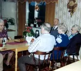 Fem äldre personer sitter runt ett bord i dagrummet/matsalen på Brattåshemmet hösten 1979. Mannen i mitten med slips är Anselm Zackrisson (1900 - 1987), övriga är okända.