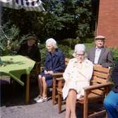 Fyra äldre personer sitter utomhus då det firas midsommar utanför Brattåshemmet 1980. Namnuppgifter saknas.