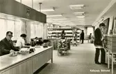 Vykort med interiör från Kållereds Bibliotek på Hagabäcksleden 9, 1970-tal. Till vänster bakom disken sitter föreståndare Ivar Andersson och kontorist/