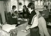 Biblioteksassistent Ingrid Hansson (sittande till vänster) vid utlåningsdisken på Kållereds bibliotek 1980-tal.