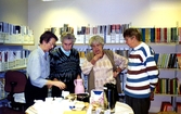Fyra kvinnor samtalar runt ett kaffebord framför hyllorna i Kållereds bibliotek 1990-tal. Ett arrangemang anordnat av Hembygdsföreningen. Från vänster: Inga Brandin, Lily Edvardsson, Eivor Bjerrhede samt Greta Nilsson. Samtliga från Hembygdsföreningen.