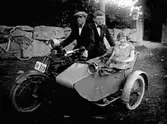 PERSSON FRÅN ÄNG I TÖREBODA PÅ SIN MOTORCYKEL MED SIDOVAGN, SAMT YTTERLIGARE EN MAN OCH EN KVINNA. REG NR R319