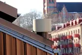Takfläkt. Byggnadsdetalj från något av husen med adresserna Bergmansgatan 4, 6, 8 och 10 i Mölndals Centrum. I bakgrunden ses även bostadshus vid Tempelgatan samt Fässbergs kyrka. Fotografi taget den 26 februari 2018. Byggnadsdokumentation inför rivning.