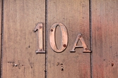 Nummer på ytterdörr. Byggnadsdetalj från lägenheten Bergmansgatan 10 A i Mölndals Centrum. Fotografi taget den 26 februari 2018. Byggnadsdokumentation inför rivning.