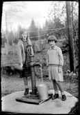 Två flickor vid vattenpump