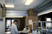 En kvinnlig personal står vid en kassaapparat i Brattåsgårdens matsal (på Streteredsvägen) cirka 1986 - 1990.