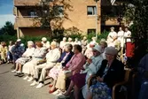 Midsommar utanför Brattåsgården, cirka 1990. Främre raden från vänster: Hulda Olsson (i rullstol), 2. Gunvor Olsson, 3. Okänd man, 4. Gunvor Johansson (röda skor), 5. Okänd kvinna, 6. Ingrid Rosén (vit hatt), 7. Helga Posse (blommig klänning).