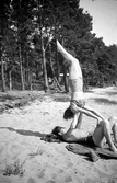 Två ungdomar har gymnastikövningar på en strand i Jönköpings kommun.