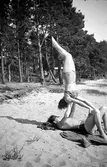 Två ungdomar har gymnastikövningar på en strand i Jönköpings kommun.