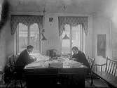 Redaktör Filip Pärson (till vänster) och redaktör Gustaf A Jansson vid sina skrivbord på Falkenbergspostens redaktion. Interiör från kontor, tidningsredaktion.