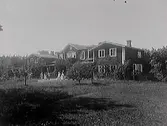 Mangårdsbyggnaden och trädgården på Knobesholms gård (1910-tal). Personerna på bilden är troligen medlemmar ur familjen Waern som då ägde gården.