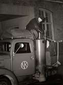 En uniformklädd man lastar Nordiska Kompaniets första gengasbil 1941.