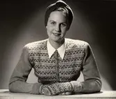 Mode visas på Nordiska Kompaniet 1944. En kvinnlig modell sitter iklädd mönstrad kofta och tumvantar i Bohus stickning.