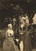 Två damer med parasoll i Skogaholms trädgård. 