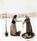 Slakt. Två kvinnor sköljer fårtarmar på vintern utomhus. 
