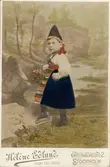Liten flicka i folkdräkt med en blomsterkorg på armen