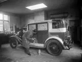 Bilsprutning Malmö. Interiör verkstad eller industri. En man sprutmålar en bil.