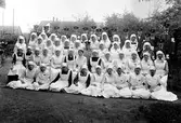 Röda korset. Gruppbild ute. En mängd kvinnor och män i rödakorsuniformer.
