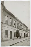Postkort - Maria (Mia) Petersén och Ragnhild Nyman utanför hattfabriken Aug. Ekströms Eftr. på Svartbäcksgatan 8, Uppsala, omkring 1910